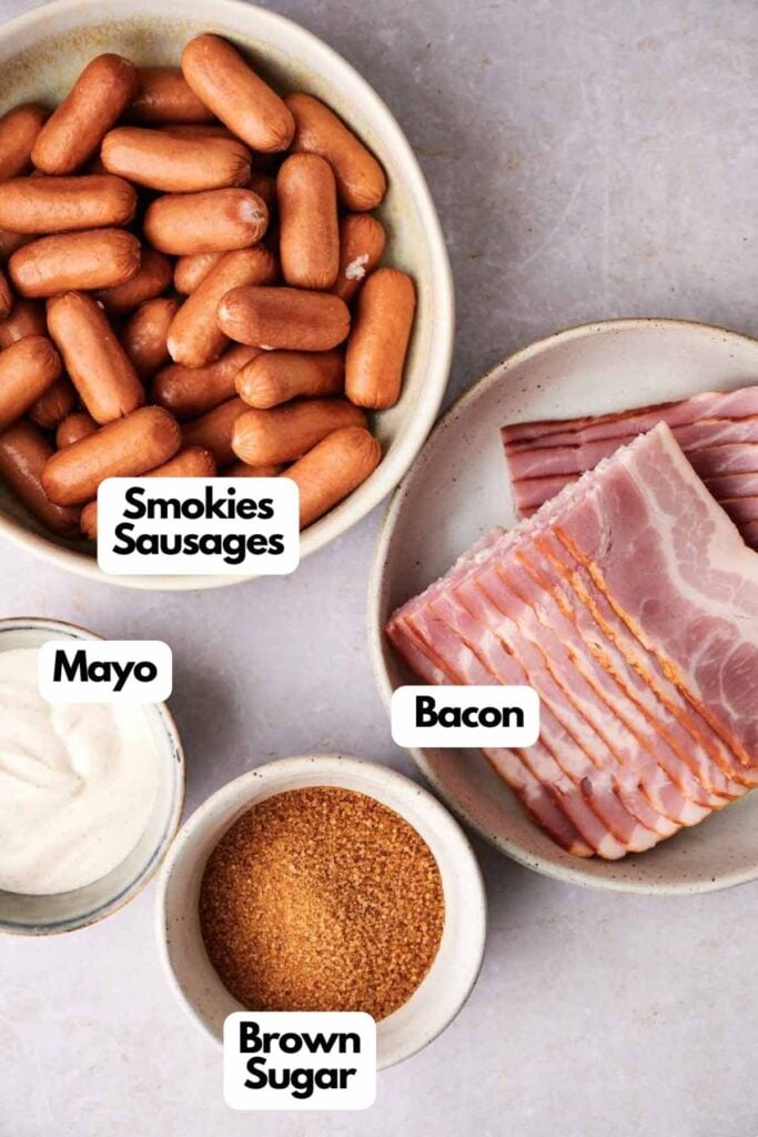 Bowls containing smokies sausages, bacon slices, mayonnaise, and brown sugar are arranged on a gray surface with labels.