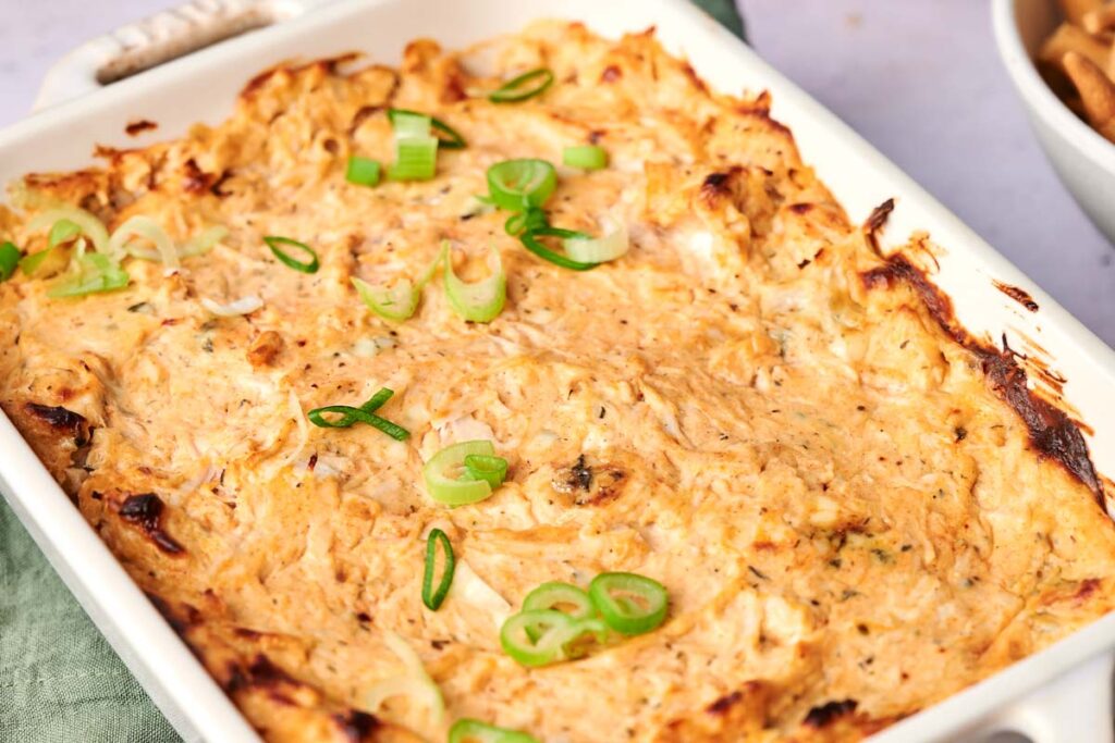 Baked casserole topped with sliced green onions in a white rectangular dish.