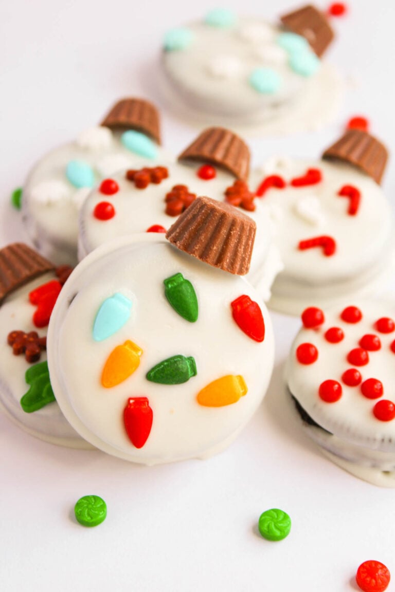 Oreo Christmas Ornament Cookies are decorated with white icing, red and green candies, and mini peanut butter cups on top, transforming the classic treat into festive holiday delights.