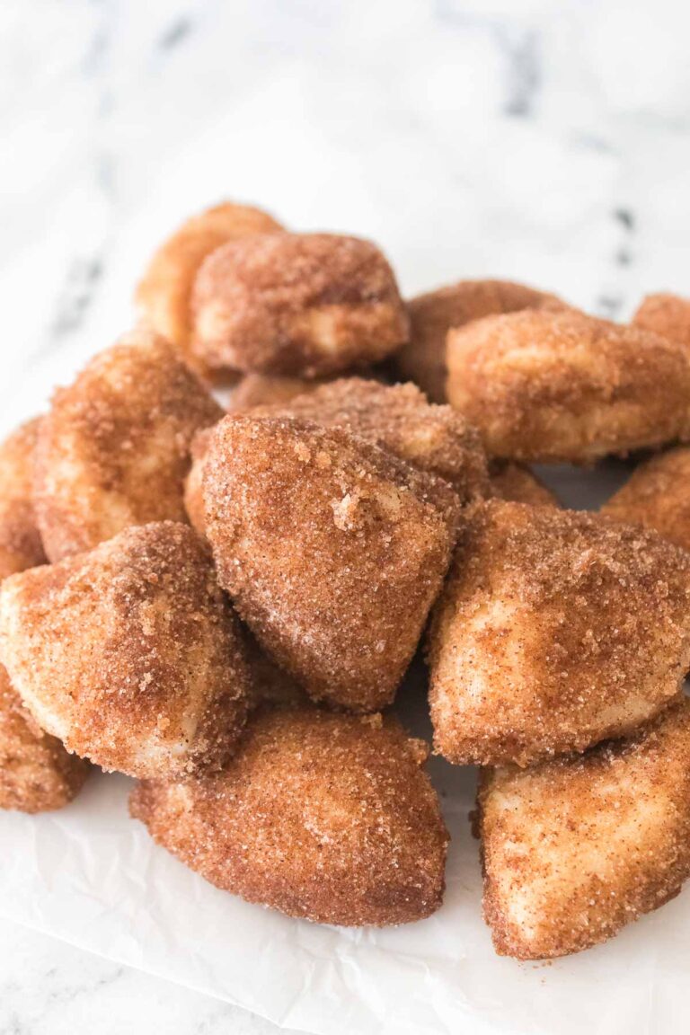 A tempting pile of Cinnamon Sugar Biscuit Bites rests on a pristine white surface, each piece perfectly coated in a sweet, spiced bliss.