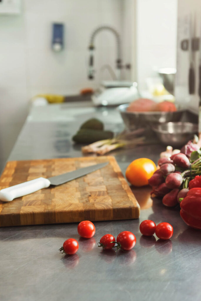 Kitchen counter with a cutting board, knife, and various vegetables including tomatoes and radishes.