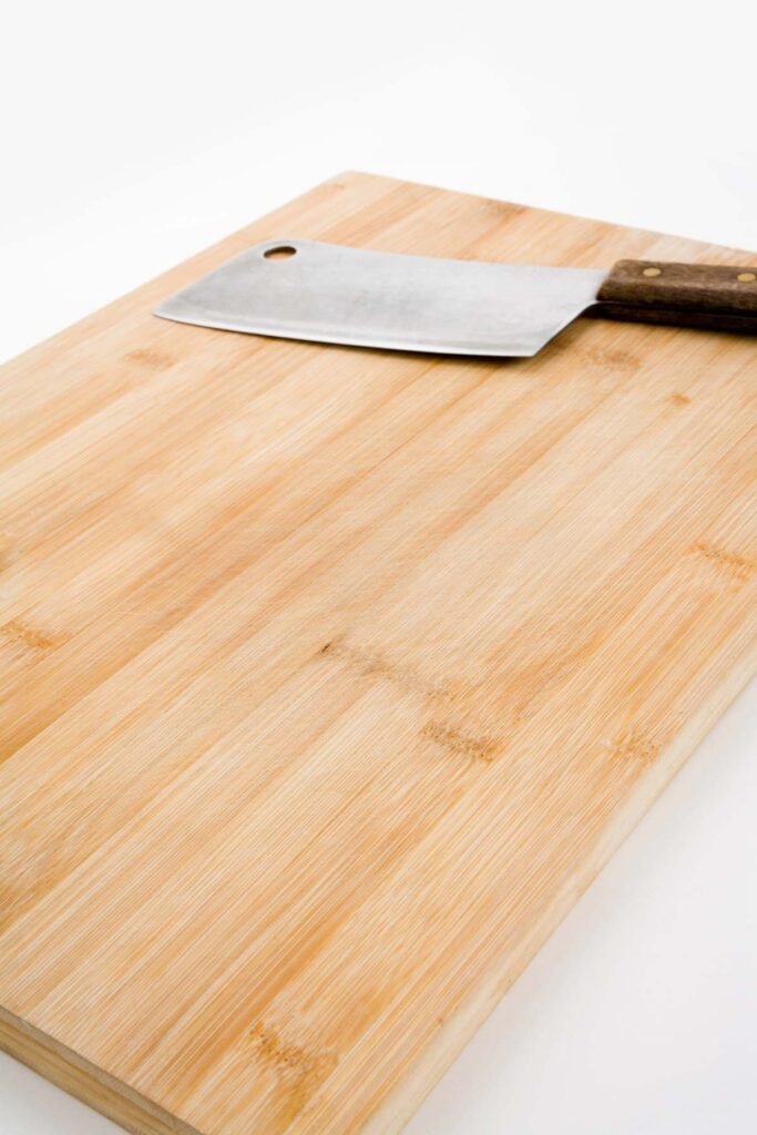 A wooden cutting board with a large cleaver knife resting on top.