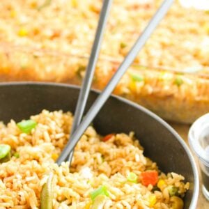 A bowl of oven-baked mixed vegetable fried rice sits invitingly, with two black chopsticks elegantly resting on top.