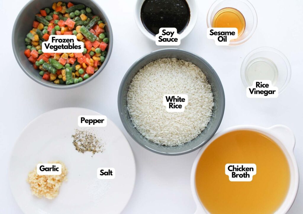 A top view of ingredients for Oven Baked Fried Rice, including frozen vegetables, white rice, soy sauce, sesame oil, rice vinegar, chicken broth, garlic, salt, and pepper.