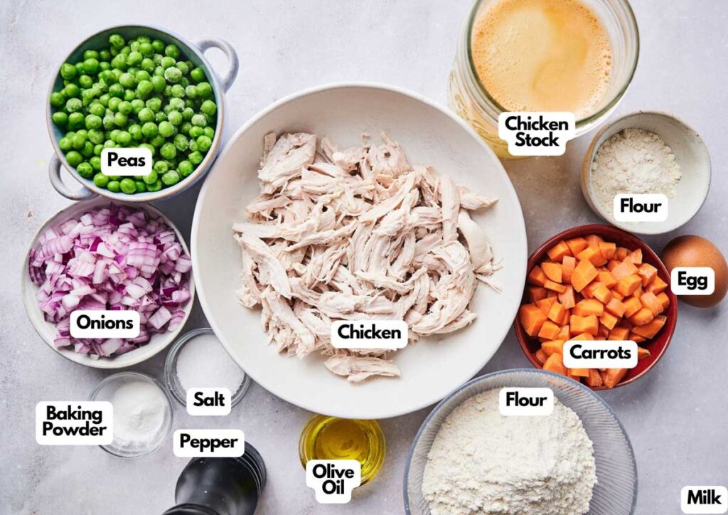 A variety of ingredients for a comforting dish, including shredded chicken, peas, onions, carrots, flour, milk, egg, chicken stock—perfect for making a hearty chicken pot pie or a savory chicken noodle casserole.