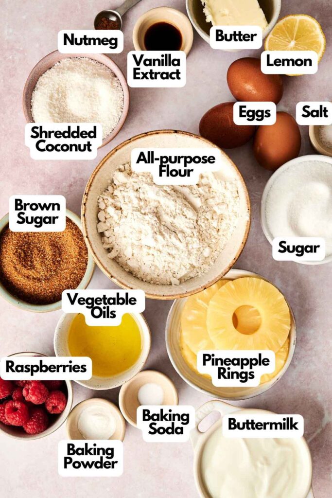 Labeled ingredients on a table include flour, sugar, raspberries, pineapple rings, eggs, vanilla extract, lemon, nutmeg, butter, brown sugar, shredded coconut, salt, and more.