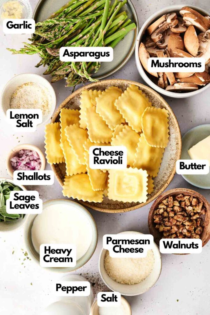 Ingredients for a delightful ravioli casserole arranged on a table: cheese ravioli, fresh asparagus, earthy mushrooms, crunchy walnuts, fragrant sage leaves, garlic cloves, creamy butter, aromatic shallots, rich heavy cream, Parmesan cheese shavings, zesty lemon salt, plus pepper and salt.