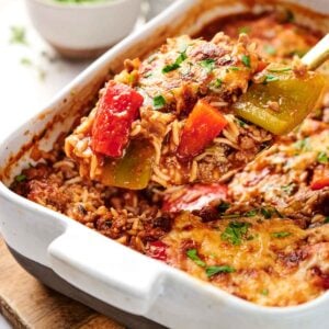 A stuffed pepper casserole features a delightful blend of baked rice, sliced red and green bell peppers, all smothered with melted cheese on top.