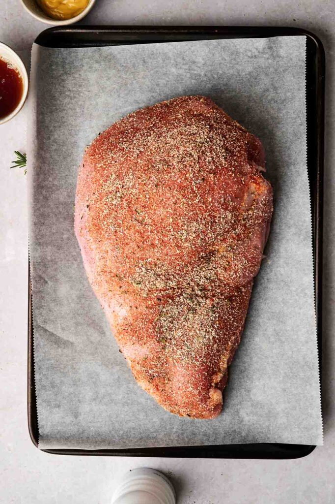 Raw seasoned meat placed on a parchment-lined tray, ready for cooking.