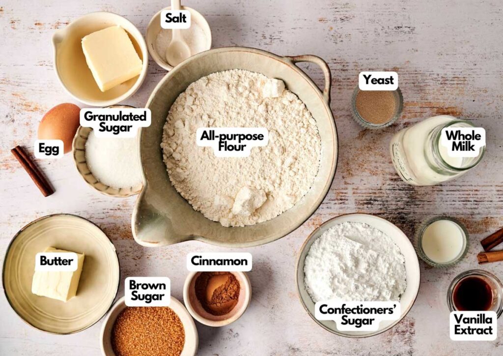 Ingredients for baking a cinnamon roll cake include all-purpose flour, granulated sugar, butter, brown sugar, confectioners’ sugar, egg, salt, cinnamon, yeast, whole milk, and vanilla extract.