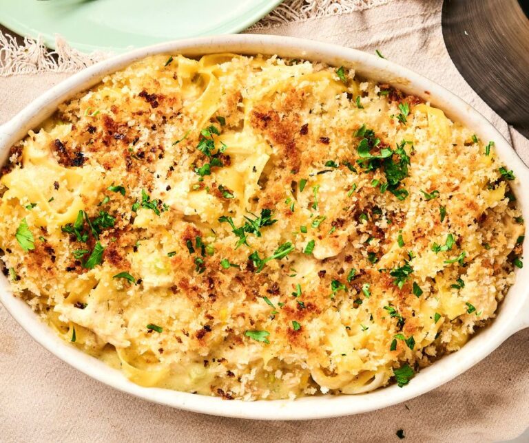 Air Fryer Chicken Noodle Casserole, baked to perfection, features pasta with a crispy breadcrumb topping, garnished with chopped herbs in a white oval dish.