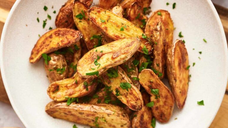 A plate of roasted fingerling potatoes garnished with chopped parsley.