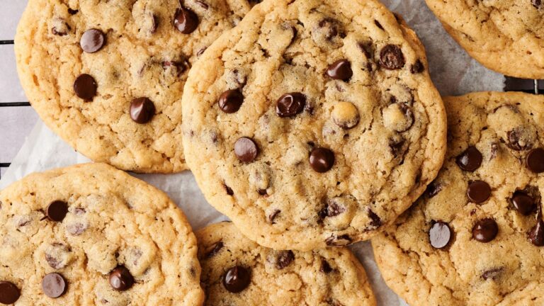 Close-up of several chocolate chip cookies on a parchment-lined surface.