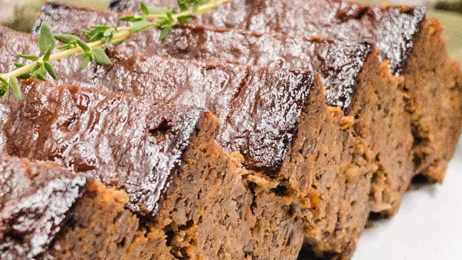 A slice of lentil loaf on a plate with sprigs of thyme.