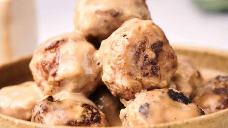 Close-up of a bowl of meatballs covered in creamy sauce.