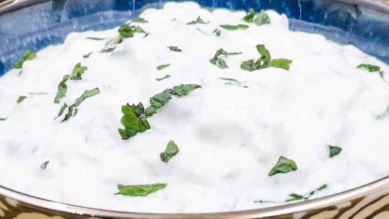 Tzatziki in a bowl with sliced veggies surrounding it.