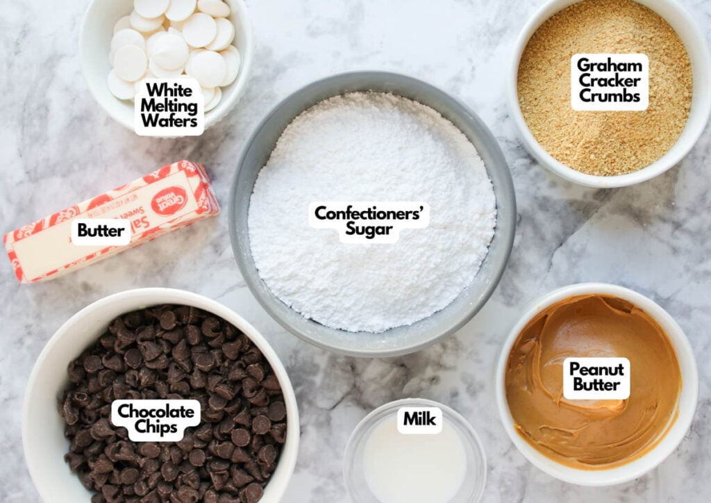 A stick of butter, white melting wafers, graham cracker crumbs, confectioners' sugar, chocolate chips, and peanut butter in separate bowls on a marble surface&mdash;perfect for making delicious peanut butter balls.