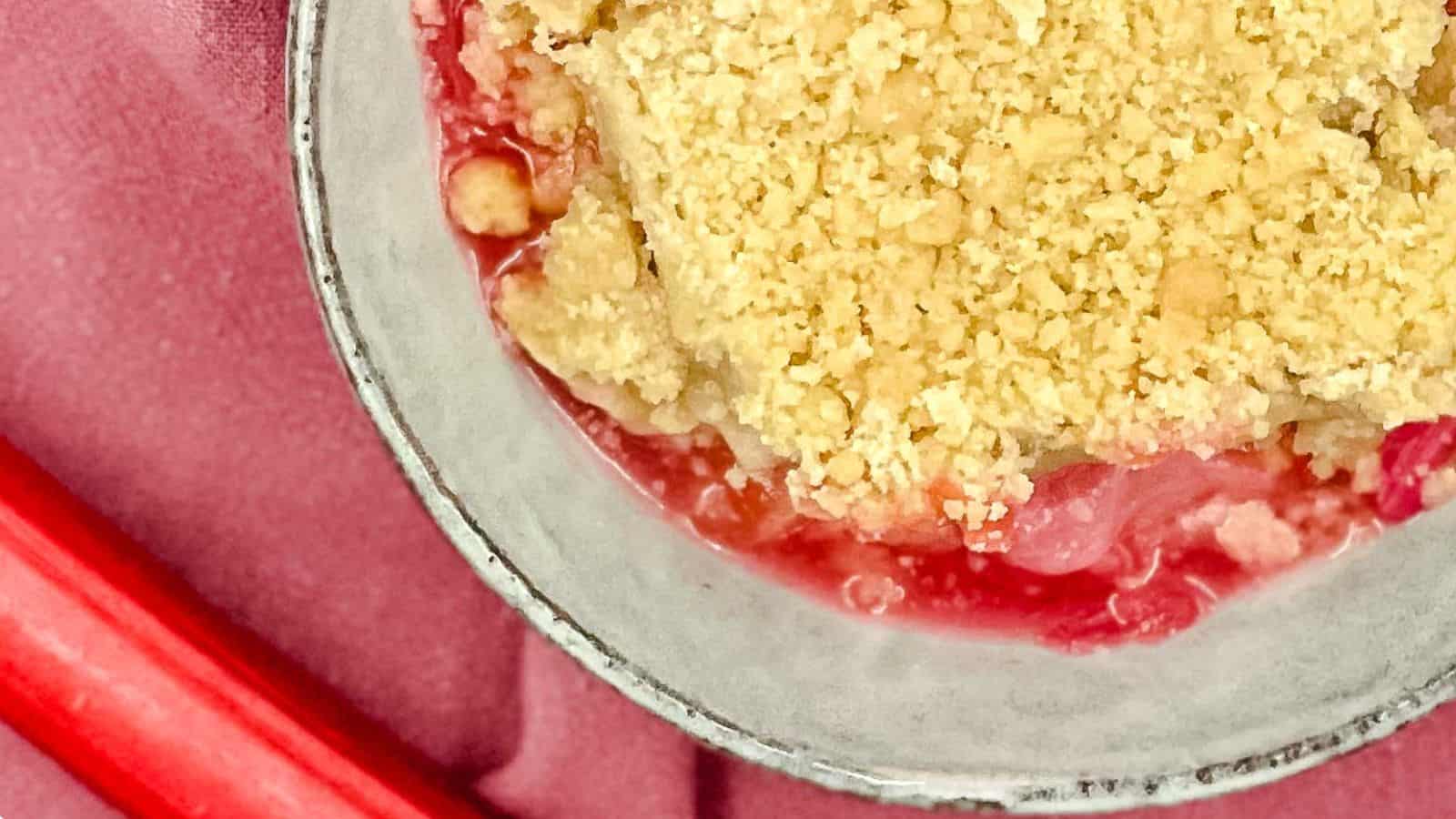 Top down shot of apple rhubarb crumble in a bowl with a scoop of ice cream.