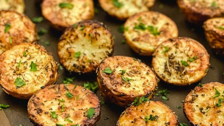 Roasted halved potatoes seasoned with herbs and garnished with chopped parsley.