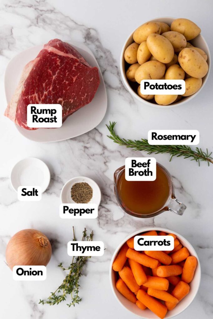 Ingredients for a roast: raw rump roast, potatoes, rosemary, salt, pepper, beef broth, onion, thyme, and carrots, arranged on a marble surface.