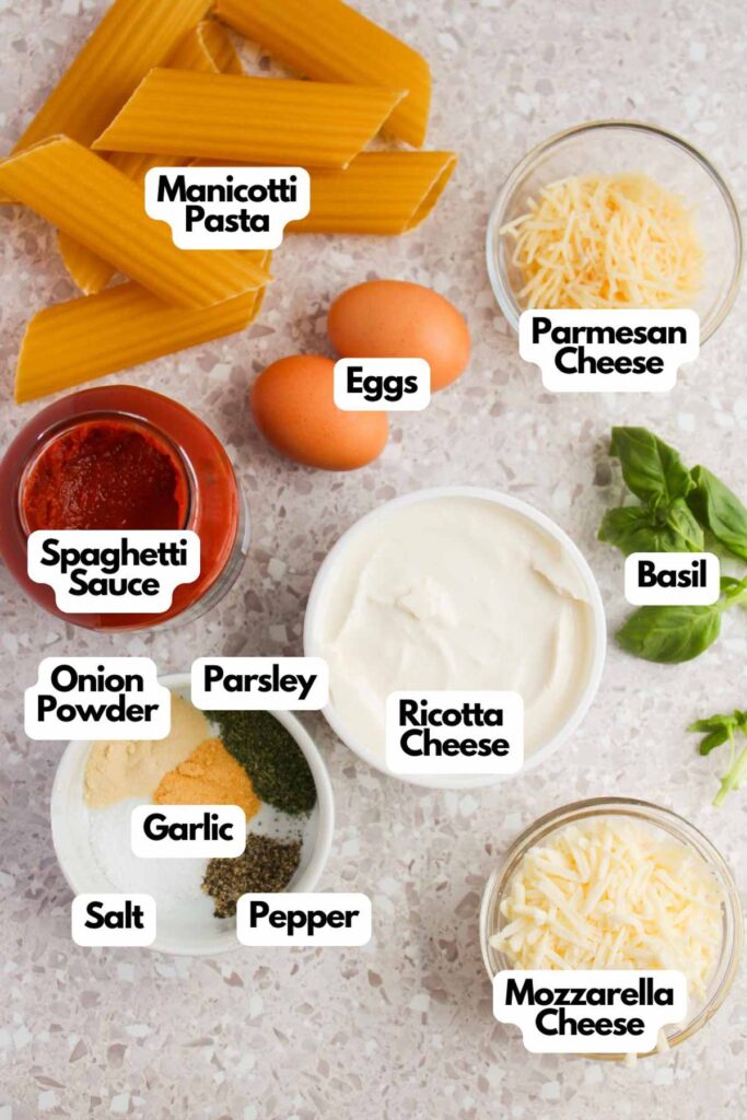 Ingredients for a Three Cheese Manicotti dish are artfully arranged on the countertop, featuring manicotti pasta, eggs, parmesan cheese, ricotta cheese, mozzarella cheese, spaghetti sauce, fresh basil, and an array of flavorful seasonings.