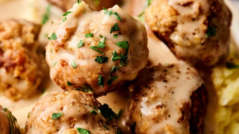 Close-up of meatballs covered in creamy sauce, garnished with parsley.