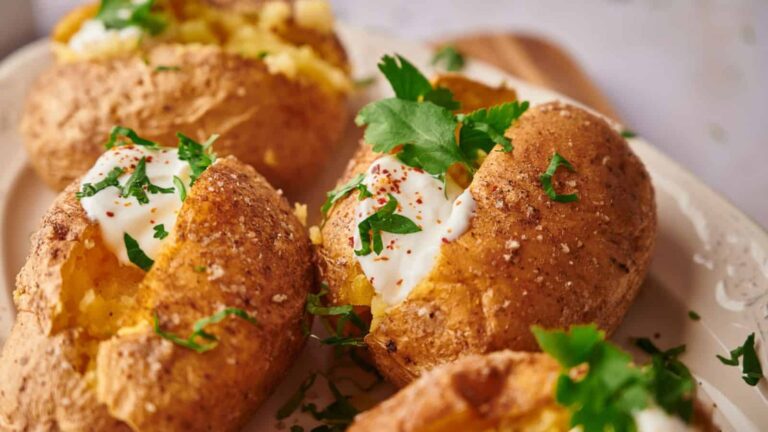 Baked potatoes topped with sour cream, chopped parsley, and a sprinkle of paprika.