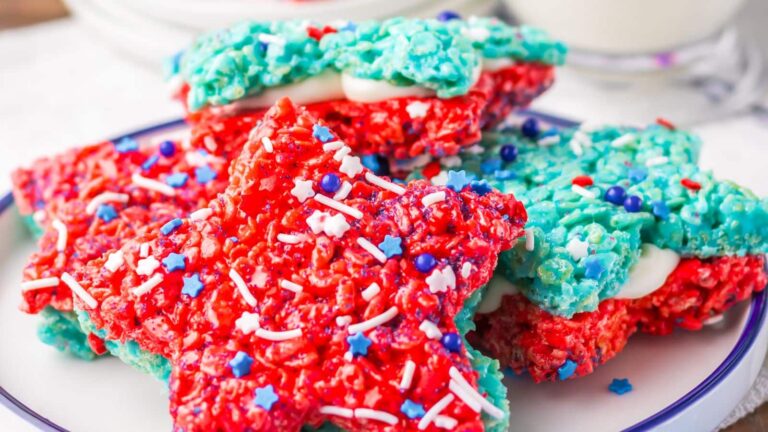 Star-shaped red and blue rice crispy treats with sprinkles stacked on a plate.