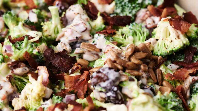 Close-up of a broccoli salad with bacon, sunflower seeds, and a creamy dressing.