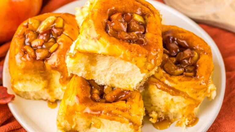 A plate of sticky apple cinnamon rolls topped with caramelized apple pieces.