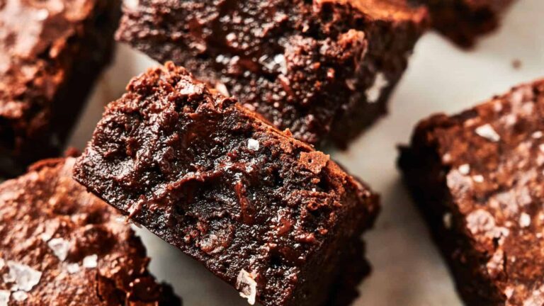 Close-up of several rich, chocolate brownies with a slightly crumbly texture and sprinkled with sea salt.