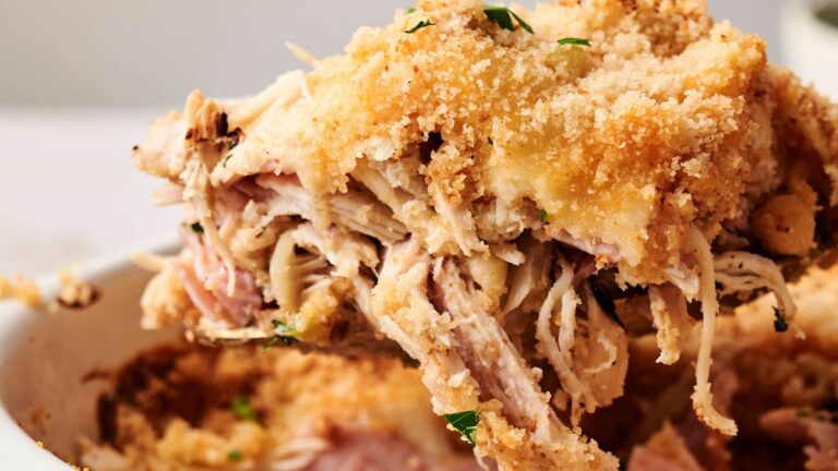 Close-up of a serving of chicken cordon bleu casserole with shredded chicken, ham, melted cheese, and breadcrumb topping, garnished with parsley.