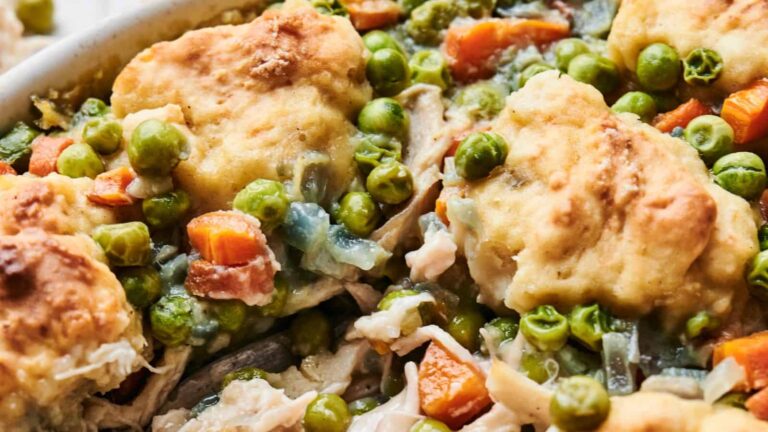 Close-up of chicken pot pie with chunks of chicken, peas, carrots, and golden biscuit topping.
