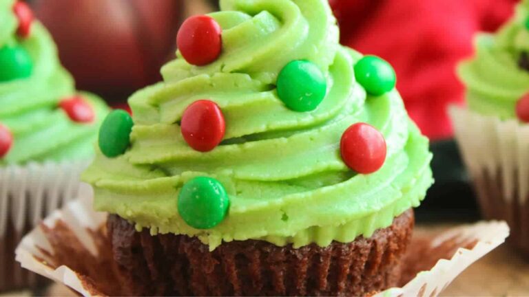 Cupcake with green frosting, decorated with red and green candy, resembling a Christmas tree.