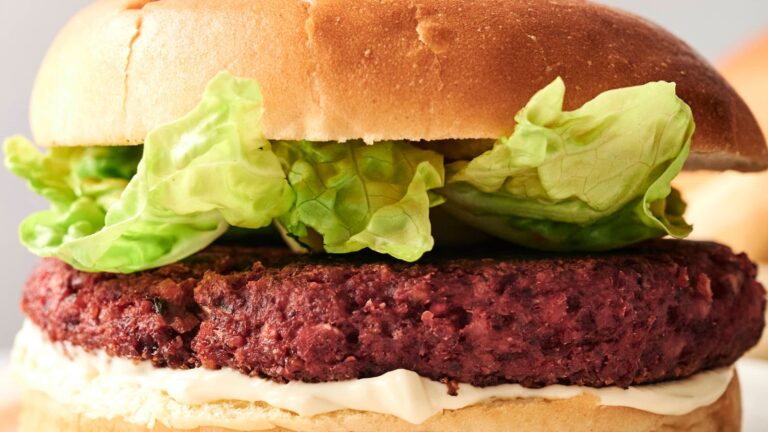 A veggie burger with lettuce and sauce in a bun.