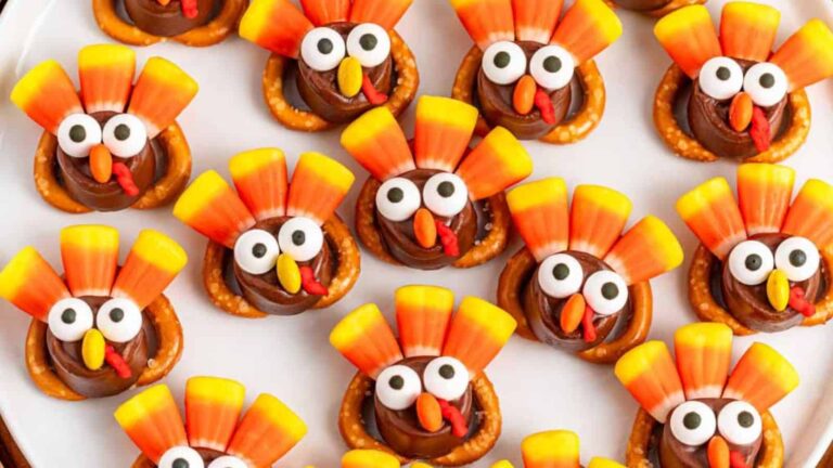 A plate of turkey-themed treats made with candy eyes, candy corn feathers, chocolate centers, and pretzel bases.