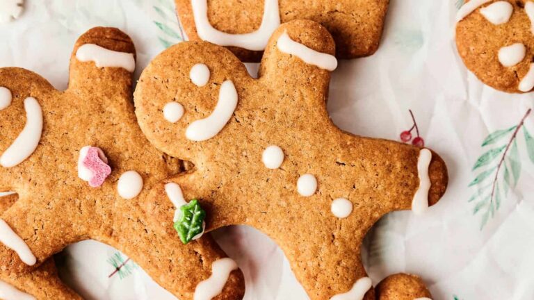 Gingerbread cookies with icing decorations on a festive background with branches and red berries.