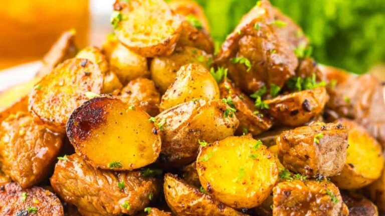 Close-up of a plate of roasted potatoes with herbs, showing a crispy golden-brown finish and garnished with parsley.