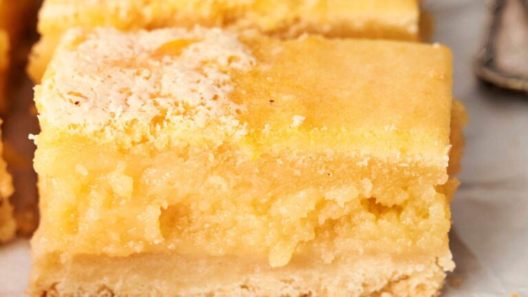 Close-up of two stacked lemon bars with a crumbly crust and creamy lemon filling.