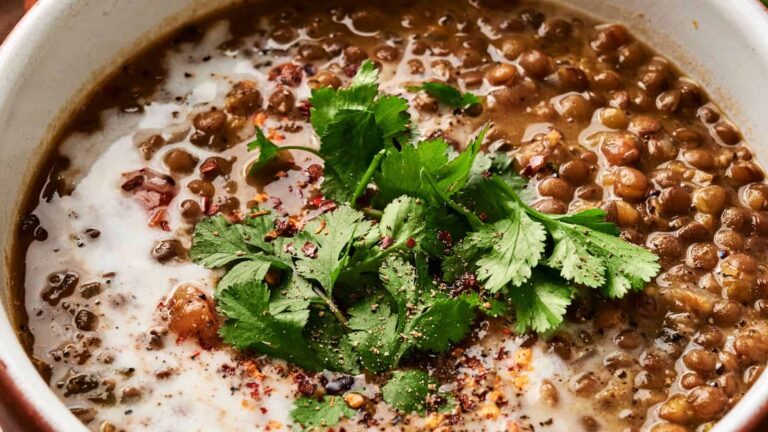 A bowl of lentil soup topped with fresh cilantro and a drizzle of cream.