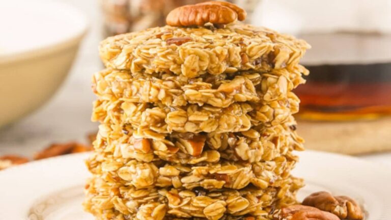A stack of oatmeal cookies with pecans on top, placed on a white plate.