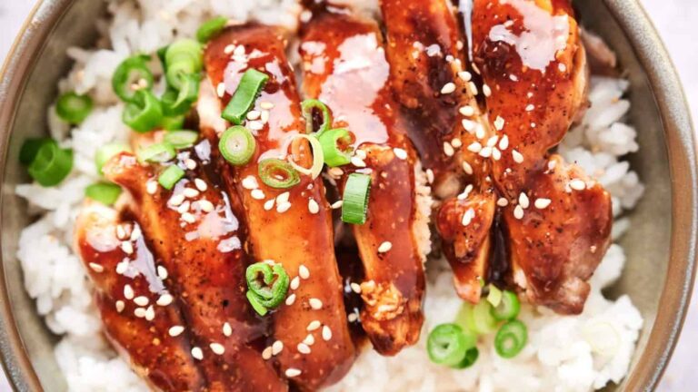 Chicken teriyaki slices topped with sesame seeds and green onions served over white rice.