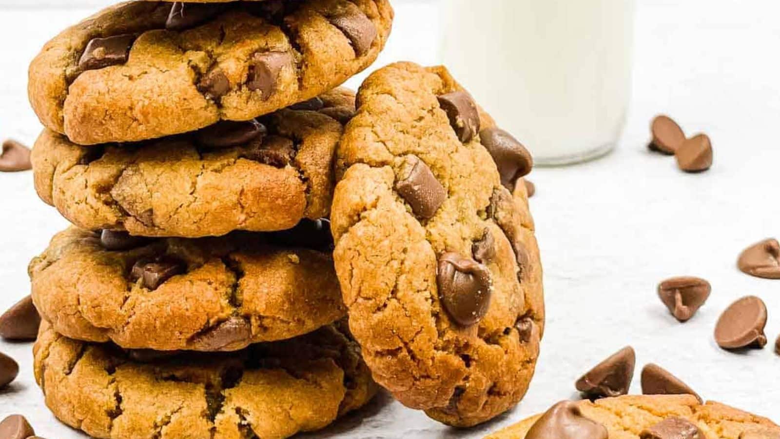 A stack of chocolate chip cookies with a glass of milk.