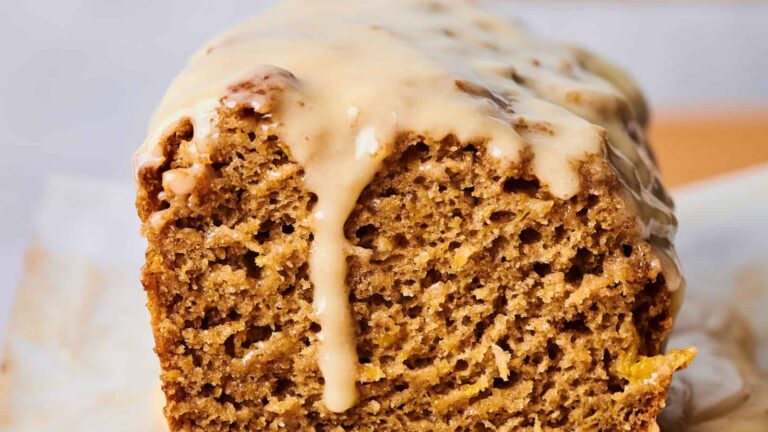 Close-up of a glazed loaf cake with a golden-brown, textured crumb.