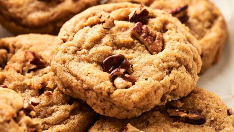 A close-up of a stack of cookies with pecans on top.
