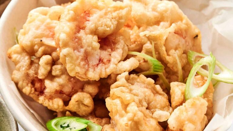A bowl of crispy tempura shrimp garnished with sliced green onions and jalapeños.
