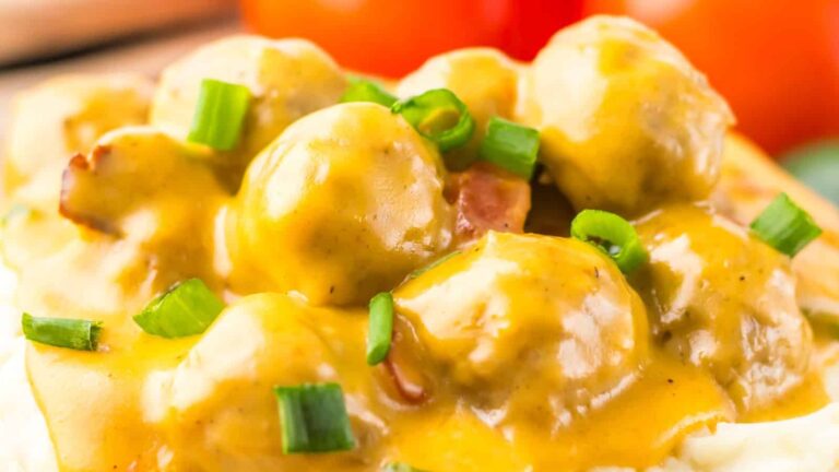 Close-up of creamy meatballs with chopped green onions on top.