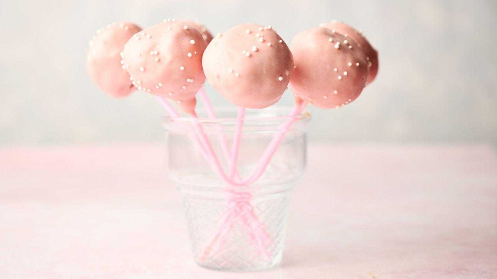 Starbucks pink cake pops in a glass on a table.