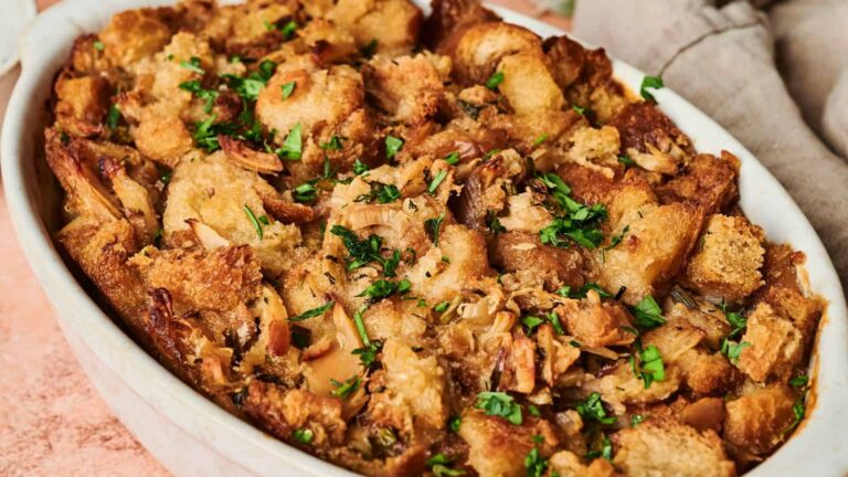 A casserole dish filled with baked stuffing topped with fresh herbs.