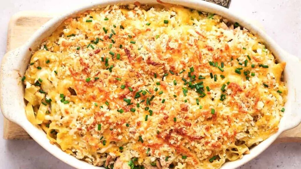 Baked casserole with a crispy, golden breadcrumb and cheese topping, garnished with chopped chives.